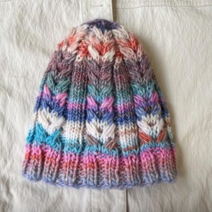 Women&#39;s hat knitted from high-quality wool. Hand-knitted multicolored wool hat. Knitted hat with colorful stripes. Warm hat handmade.