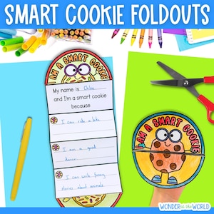 May include: A folded paper craft with the text "I am a smart cookie" and a cartoon cookie illustration. The craft is open, revealing lines for writing. A yellow pen and scissors are also visible.