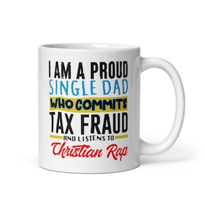 May include: White ceramic mug with the text "I am a proud single dad who commits tax fraud and listens to Christian Rap" in black, blue, and yellow lettering.