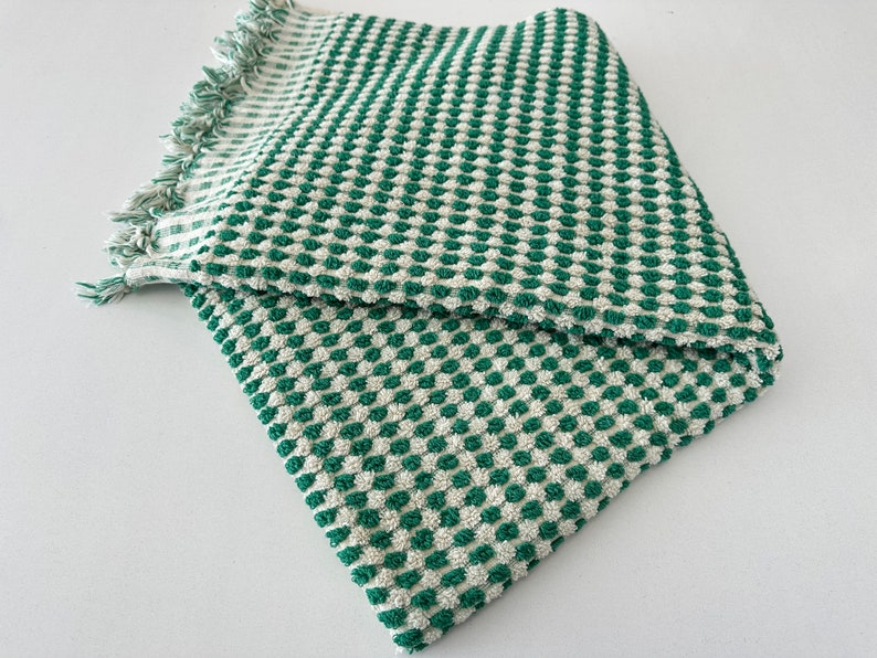 May include: A green and white checkered bath towel with a fringed edge.