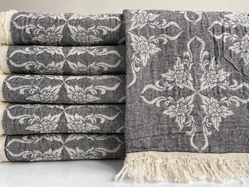Puede incluir: Una pila de seis toallas negras y blancas con flecos. Las toallas tienen un dise&ntilde;o floral y est&aacute;n hechas de un material suave y absorbente.