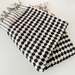 May include: Black and white patterned Turkish towel with fringe. The towel has a textured, waffle-like design.
