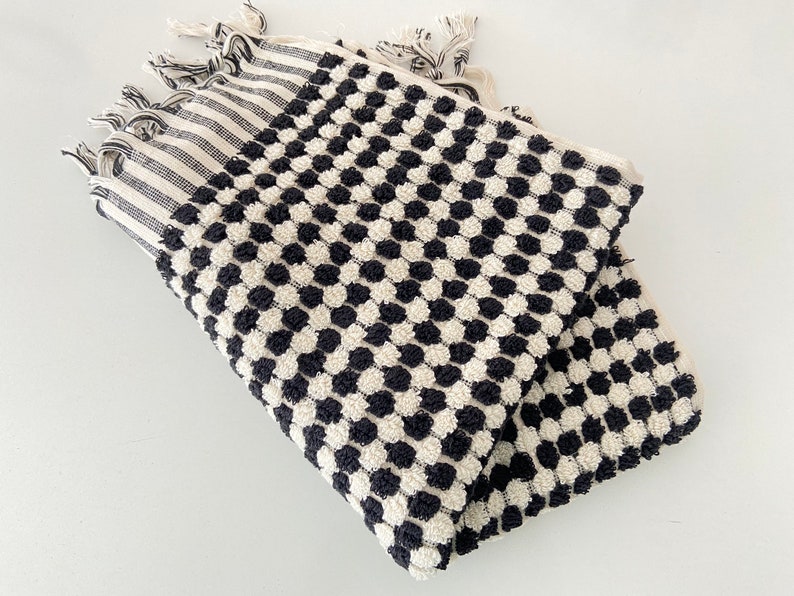 May include: Black and white patterned Turkish towel with fringe. The towel has a textured, waffle-like design.