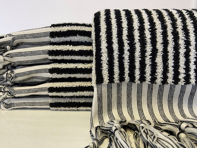 May include: A stack of black and white striped towels with fringe. The towels are made of a soft, absorbent material.