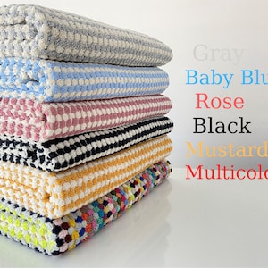 May include: A stack of six waffle weave towels in various colors, including gray, baby blue, rose, black, mustard, and multicolor.