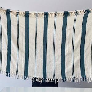 May include: A white and teal striped throw blanket with fringe on all sides.