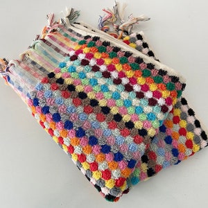 May include: A stack of colorful towels with a textured, polka dot pattern. The towels are made of a soft, absorbent material and are perfect for drying off after a shower or bath.