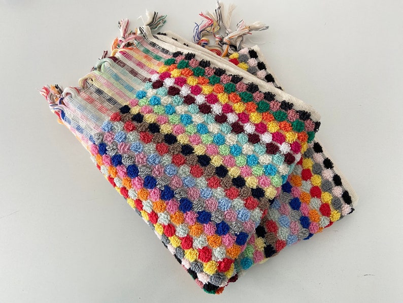 May include: A stack of colorful towels with a textured, polka dot pattern. The towels are made of a soft, absorbent material and are perfect for drying off after a shower or bath.