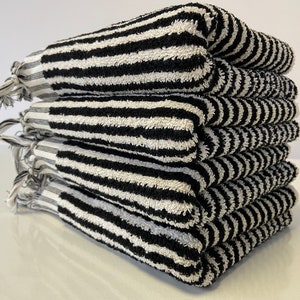 May include: A stack of six black and white striped towels with fringe edges.