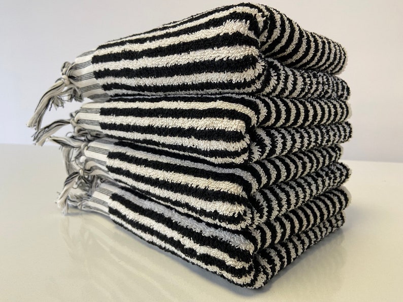 May include: A stack of six black and white striped towels with fringe edges.