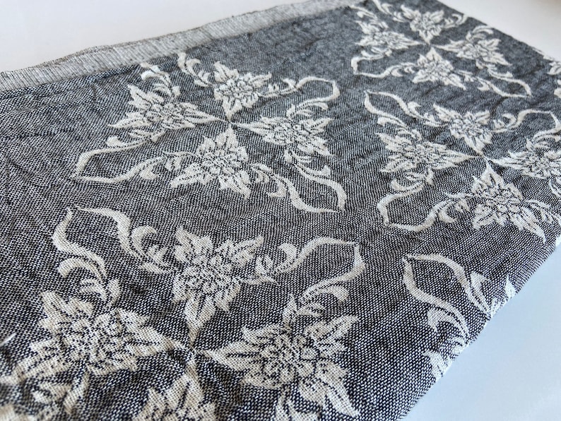 Puede incluir: Una manta de tejido suave con un dise&ntilde;o floral en blanco y negro.