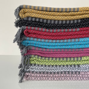 Puede incluir: Una pila de diez toallas turcas coloridas con bordes de flecos. Las toallas est&aacute;n dobladas y apiladas en una variedad de colores, incluyendo amarillo, negro, rojo, azul, rosa, verde, blanco y rosa. Las toallas tienen un patr&oacute;n geom&eacute;trico.