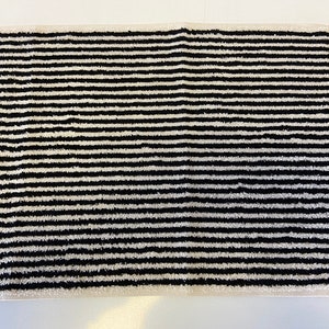 May include: Black and white striped bath mat. The mat is made of a soft, absorbent material and is perfect for drying your feet after a shower or bath.