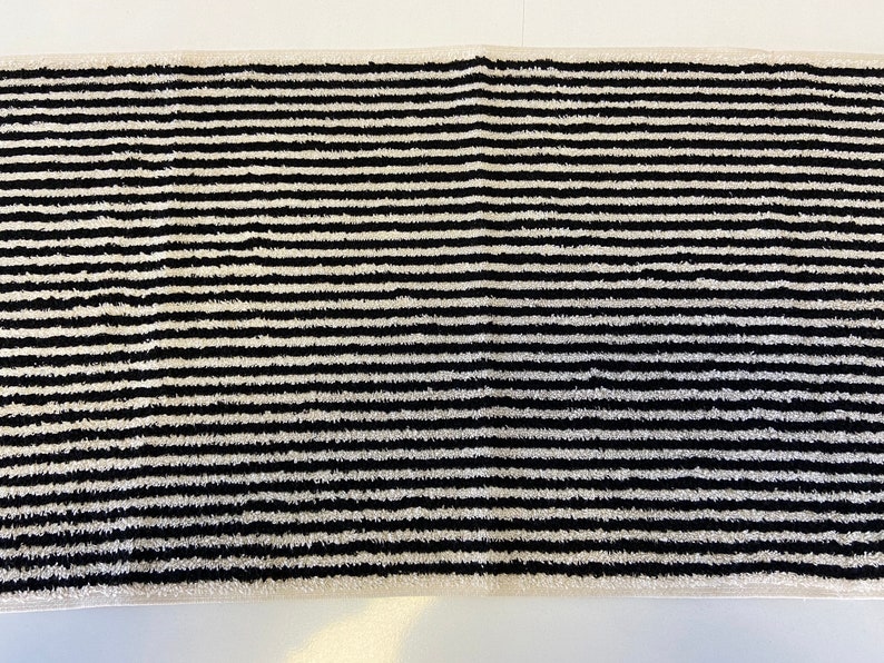 May include: Black and white striped bath mat. The mat is made of a soft, absorbent material and is perfect for drying your feet after a shower or bath.