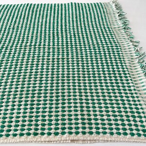 May include: A green and white waffle weave kitchen towel with a fringed edge.