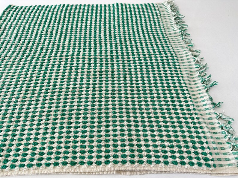 May include: A green and white waffle weave kitchen towel with a fringed edge.