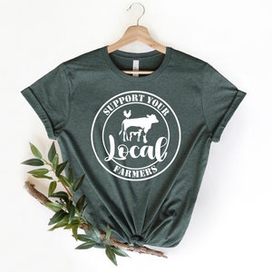 May include: A dark green t-shirt with a white circle graphic that says "Support Your Local Farmers" with a cow, calf, and chicken inside the circle.