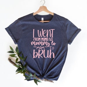 May include: A navy blue t-shirt with pink text that reads "I went from mama to mommy to -mom- to bruh".