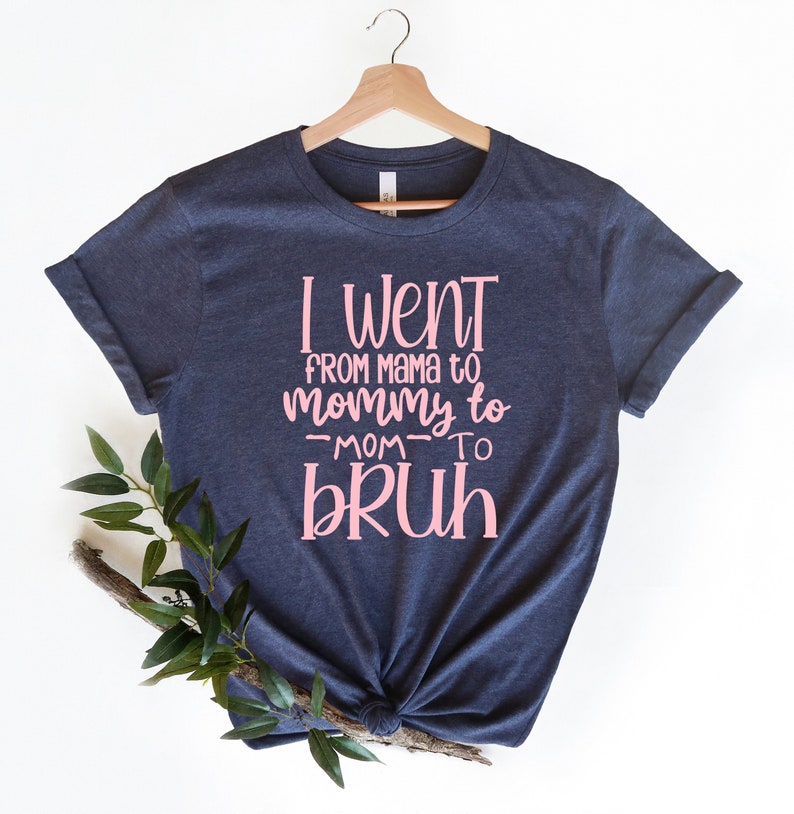 May include: A navy blue t-shirt with pink text that reads "I went from mama to mommy to -mom- to bruh".