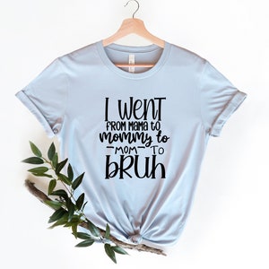 May include: Light blue t-shirt with black text that reads "I went from mama to mommy to -mom- to bruh".