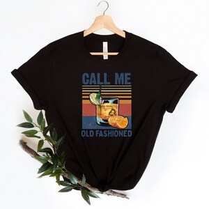 May include: Black t-shirt with a vintage-style graphic of an old fashioned cocktail with the text "Call Me Old Fashioned".