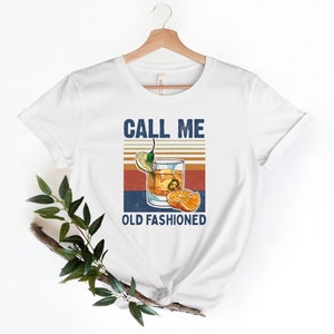 May include: White t-shirt with a vintage-style graphic of an old fashioned cocktail with the text "Call me Old Fashioned".