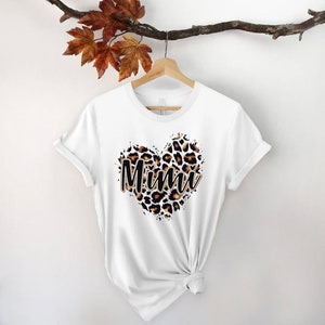 May include: White t-shirt with a leopard print heart design and the word "Mimi" in black text.