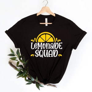 May include: Black t-shirt with a white graphic of a yellow lemon slice and the text "Lemonade Squad".