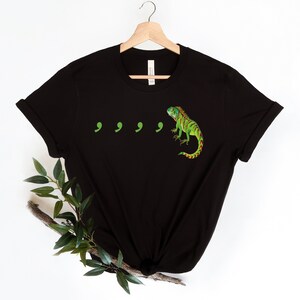 May include: Black t-shirt with a green iguana and four green commas printed on the front.