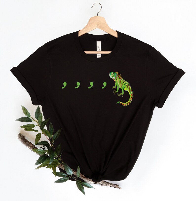 May include: Black t-shirt with a green iguana and four green commas printed on the front.