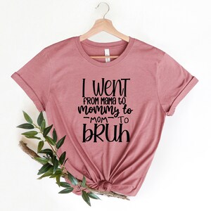 May include: A mauve t-shirt with the text "I went from mama to mommy to -mom- to bruh" printed in black.