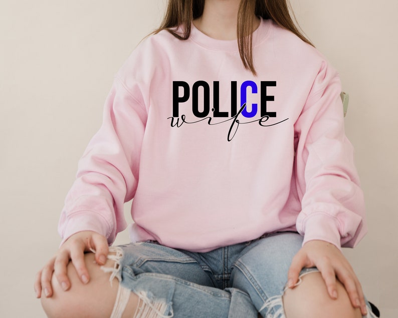 May include: Pink sweatshirt with the text "POLICE wife" in black lettering with a blue "C".