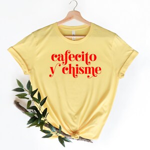 May include: Yellow t-shirt with the text "cafecito y chisme" in red.