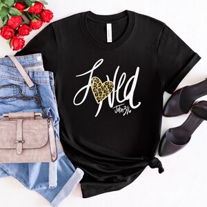 May include: Black t-shirt with a white graphic that says "Loved" with a leopard print heart and the text "John 3:16".