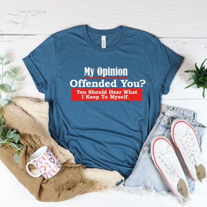 May include: A blue t-shirt with the text "My Opinion Offended You? You Should Hear What I Keep To Myself." printed in white on a red background.