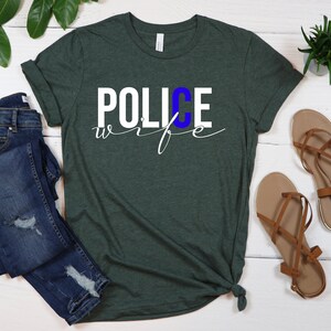May include: A green t-shirt with the words "POLICE wife" in white lettering. The "C" in "POLICE" is blue.