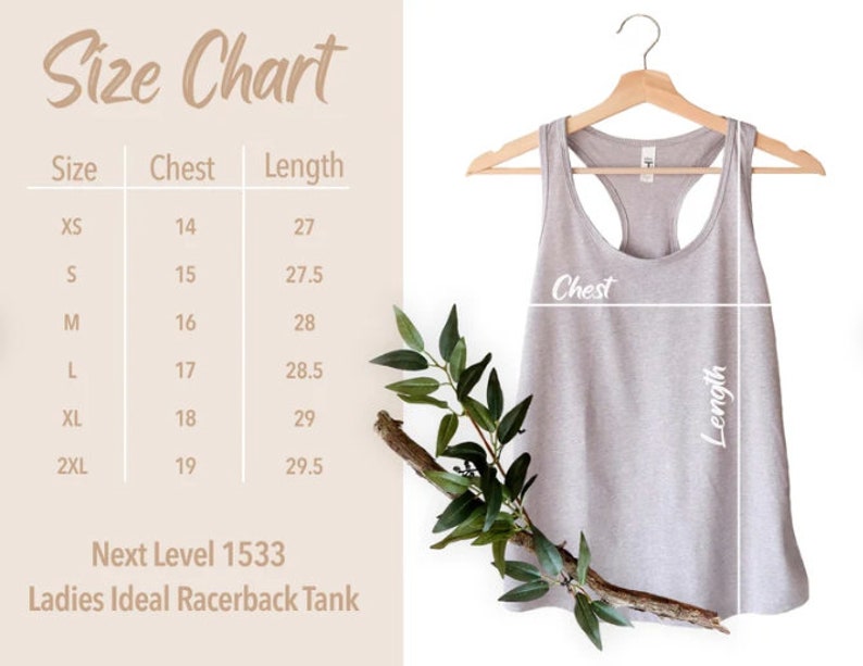 May include: Size chart for a racerback tank top with measurements in inches for chest and length. Sizes include XS, S, M, L, XL, and 2XL. The chart shows the measurements for each size. The tank top is light gray and is hanging on a wooden hanger.