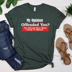 May include: A green t-shirt with the text "My Opinion Offended You? You Should Hear What I Keep To Myself." in white letters with a red rectangle behind the text.