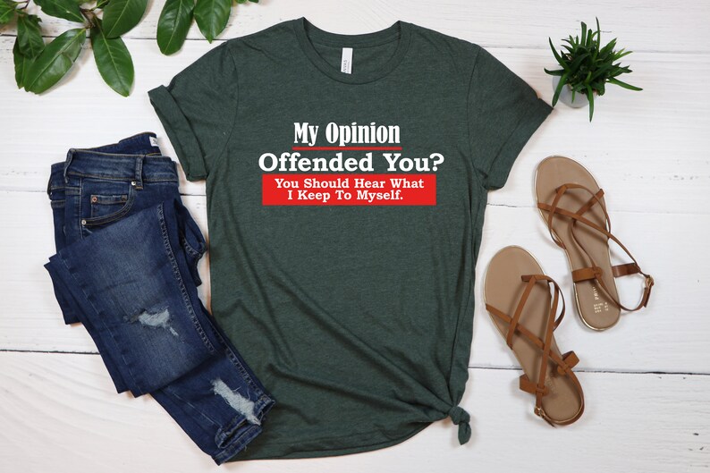 May include: A green t-shirt with the text "My Opinion Offended You? You Should Hear What I Keep To Myself." in white letters with a red rectangle behind the text.