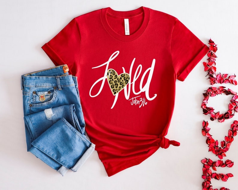 May include: Red short-sleeved t-shirt with a white graphic that says "Loved" with a leopard print heart and the text "John 3:16".
