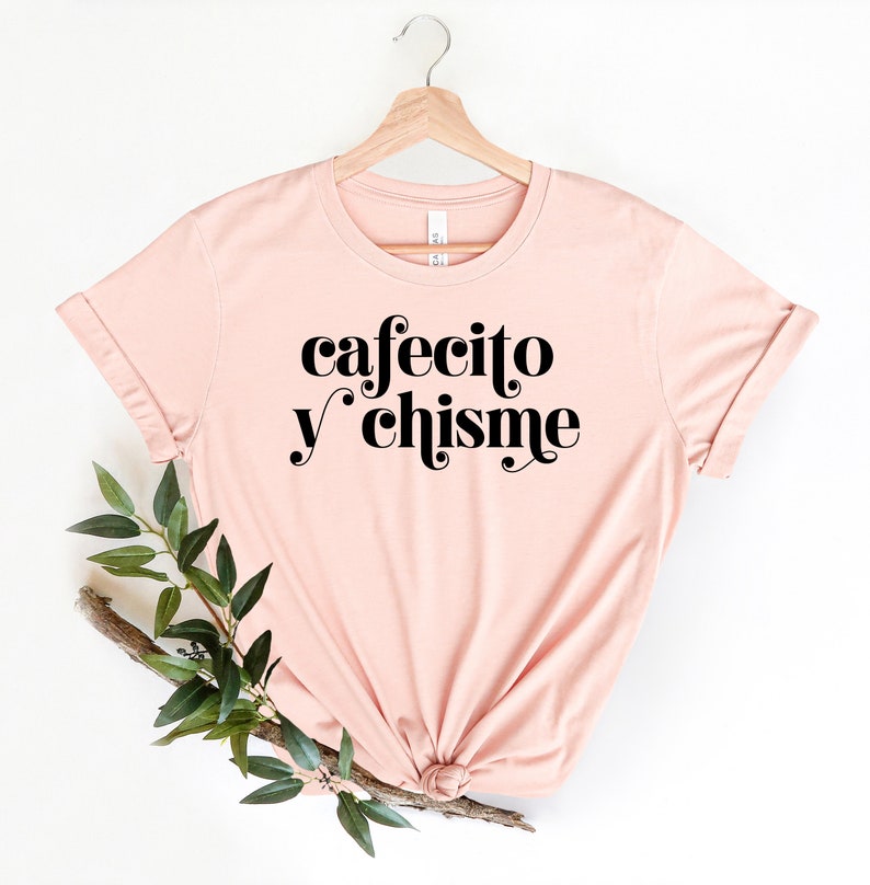 May include: A pink t-shirt with the text "cafecito y chisme" in black.
