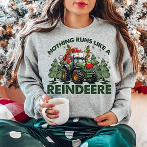 Może przedstawiać: Szara bluza z świątecznym wzorem przedstawiającym traktor z czapką Świętego Mikołaja i tekstem "Nothing runs like a Reindeere".