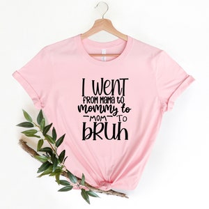 May include: Pink t-shirt with black text that reads "I went from mama to mommy to -mom- to bruh".