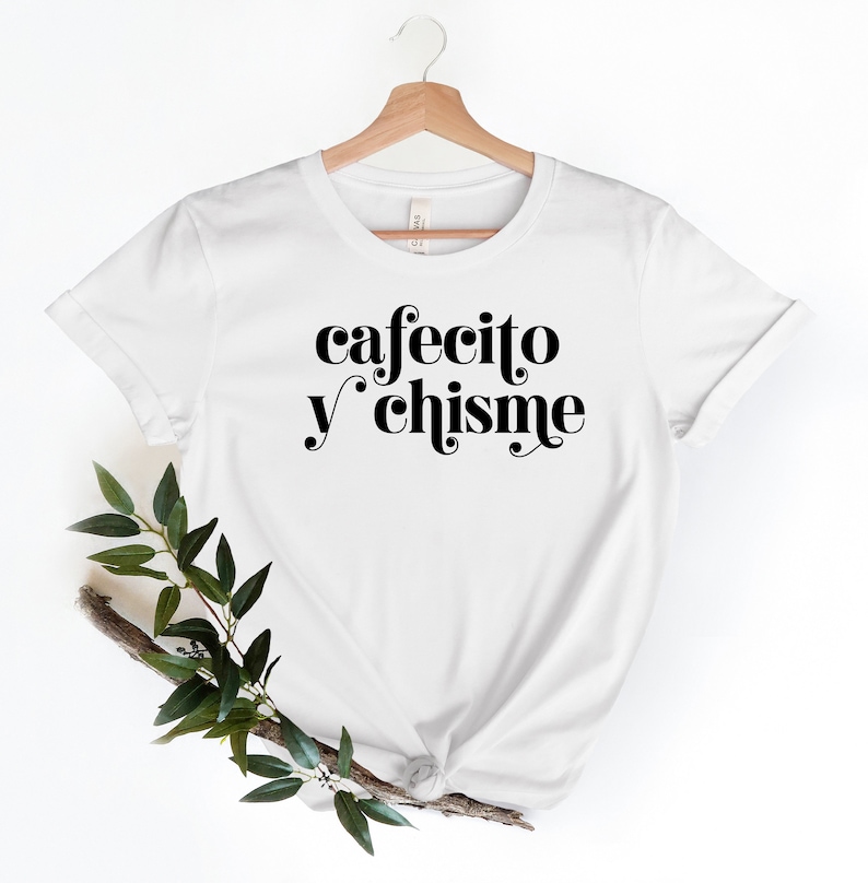 May include: White t-shirt with black text that reads "cafecito y chisme" in a retro font.