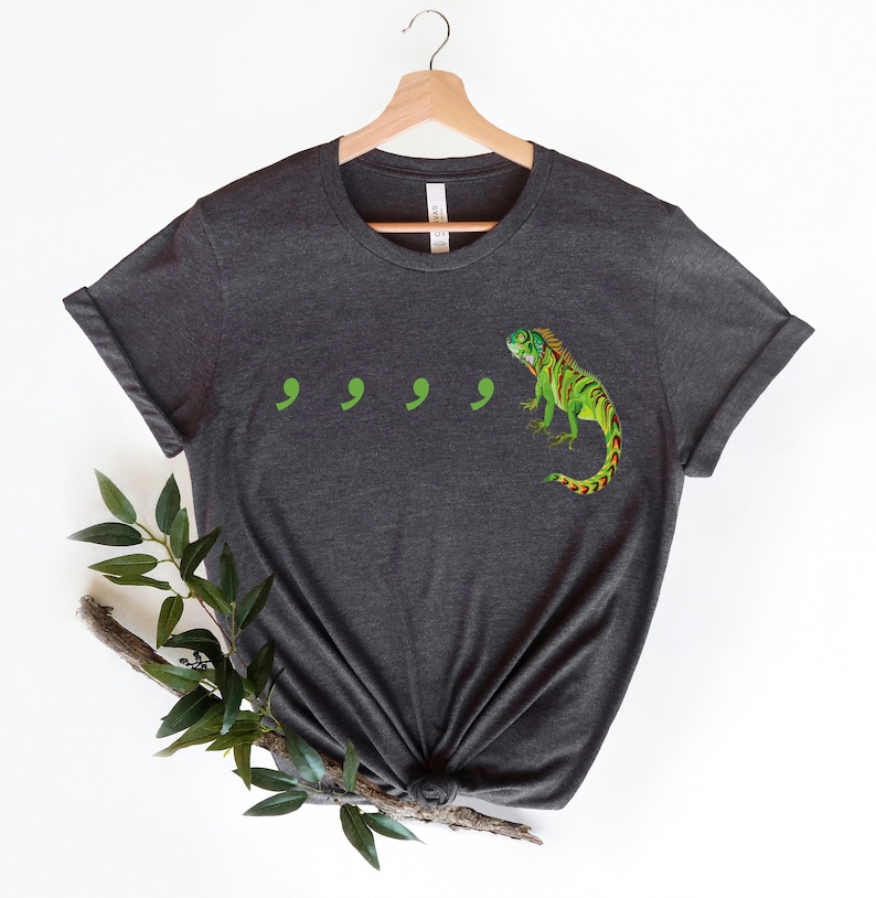 May include: Dark gray t-shirt with a green iguana and four green commas printed on the front.