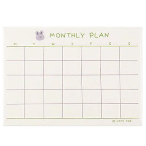 May include: A white monthly planner with a light purple bunny illustration at the top. The planner has a grid layout with the days of the week labeled: M, T, W, T, F, S, S. The bottom right corner has the text "NOTE FOR".