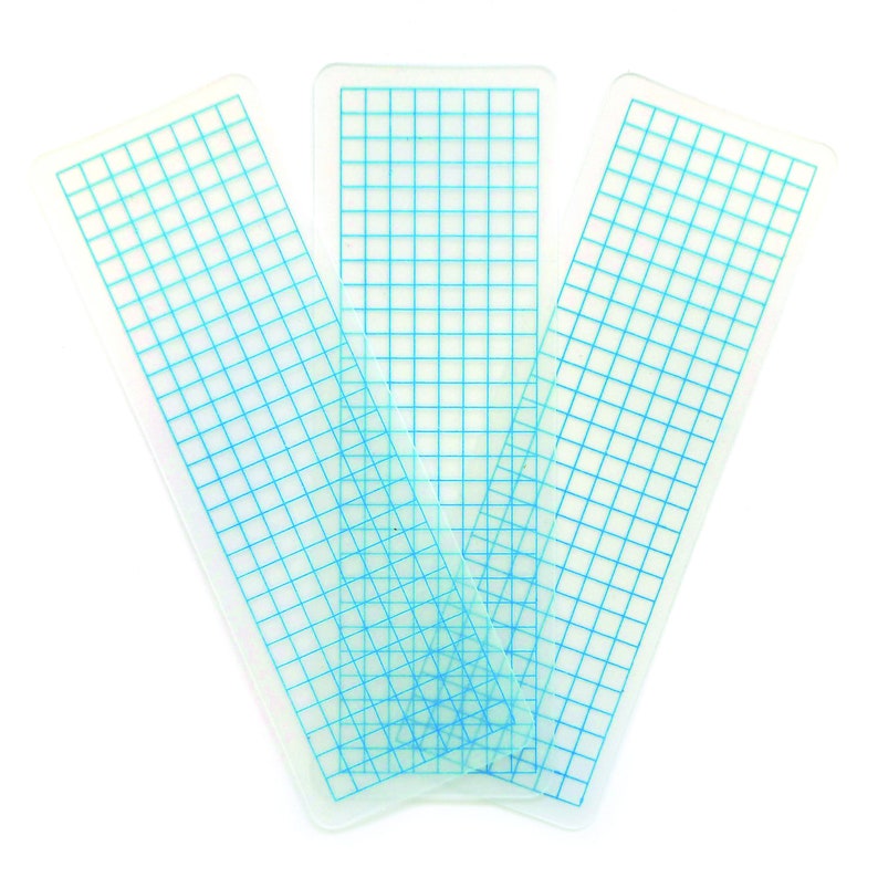 May include: Three clear plastic rulers with blue grid lines. The rulers are stacked on top of each other.