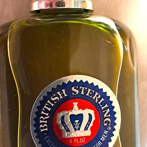 May include: A vintage cologne bottle with a silver cap and a green liquid. The label reads "British Sterling" with a crown emblem and "Exclusive Toiletries For Men". The bottle contains 1 fl oz of cologne.