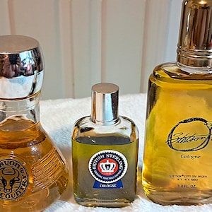 May include: Three vintage cologne bottles. The bottle on the left has a silver cap and a Wild Country logo. The middle bottle is labeled British Sterling Cologne. The bottle on the right is labeled Stetson Cologne, 3.0 fl oz.