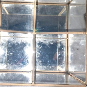 Op de afbeelding: Een set geometrische glazen en metalen displayboxen met een goudkleurig frame. De dozen zijn verdeeld in meerdere compartimenten en hebben spiegelende interieurs. Het ontwerp is modern en geschikt voor het presenteren van kleine items.